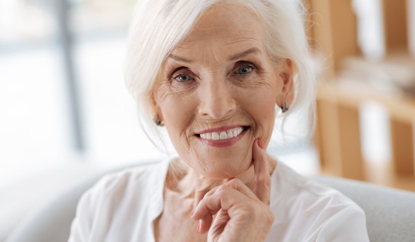 Senior woman smiling warmly at camera in bright, modern dental office setting.
