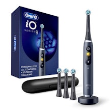 Oral-B electric toothbrush set with black handle, charging base, and replacement heads displayed with product box.