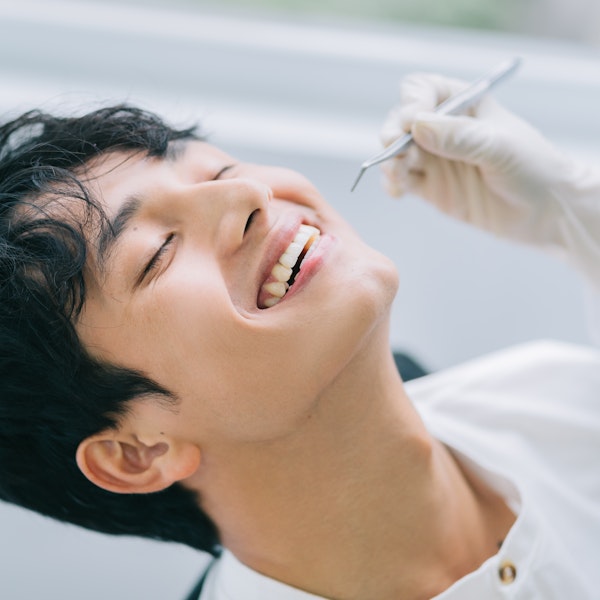 Patient receiving dental examination with dentist in white gloves at dental office visit.