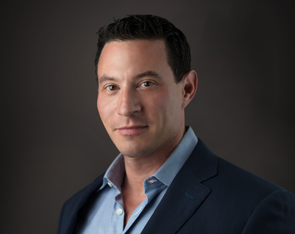 Professional headshot of a man in business attire against neutral background for dental practice website.