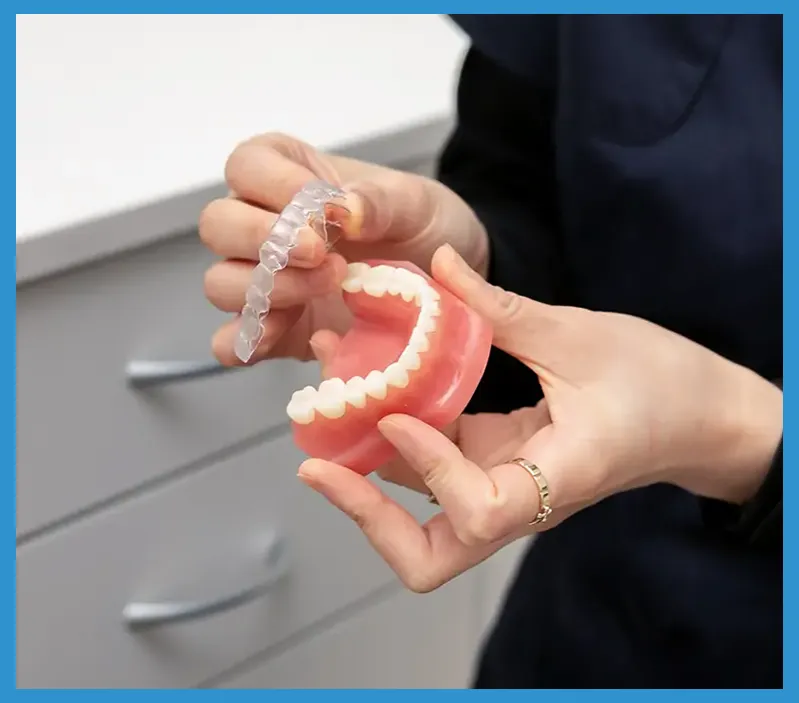 Person holding dental model and clear aligner demonstrating orthodontic treatment in clinical setting.
