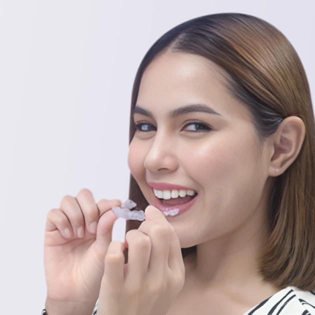 Smiling woman holding dental aligners near her mouth against white background.