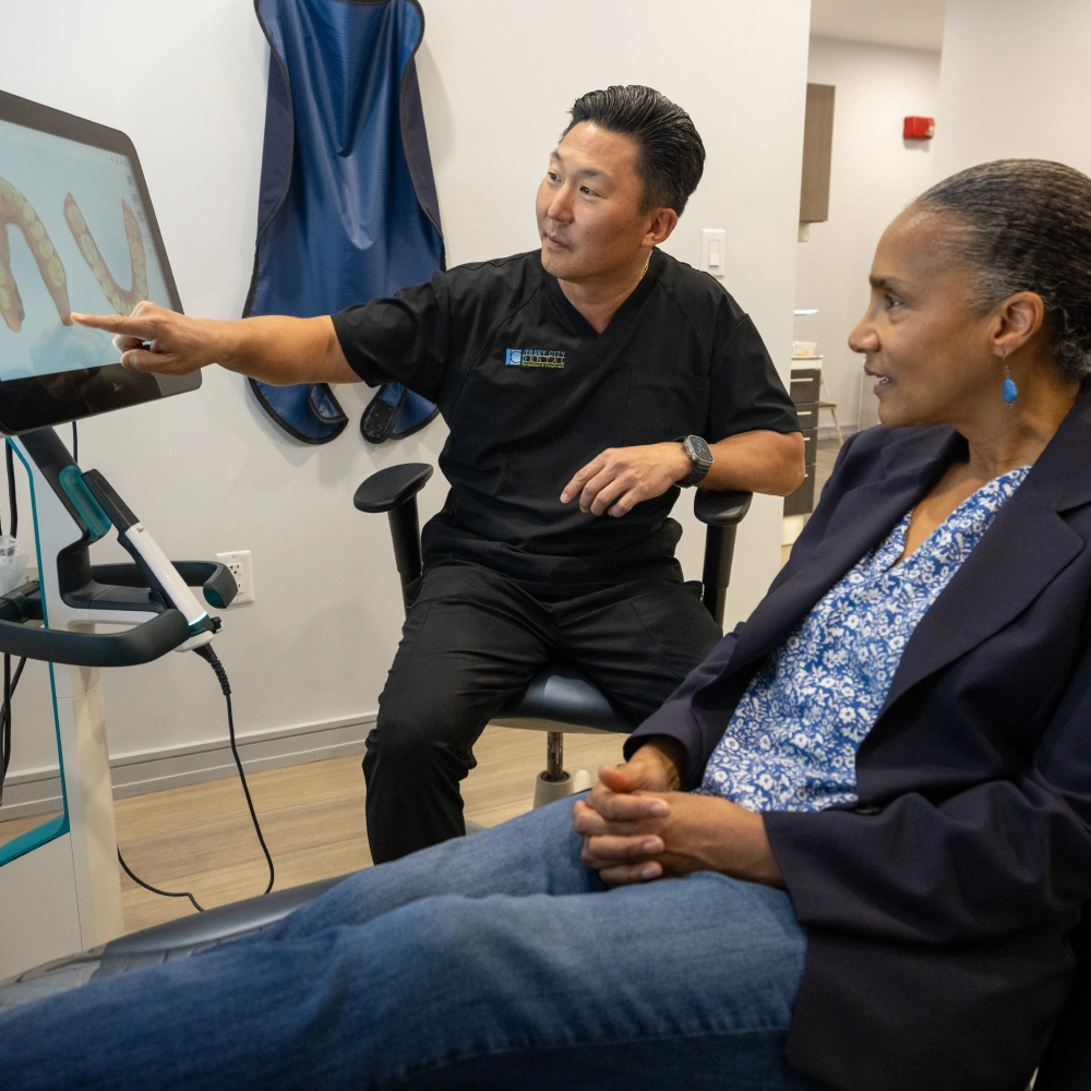 Healthcare professional demonstrates hand X-ray scan to patient in medical office setting.